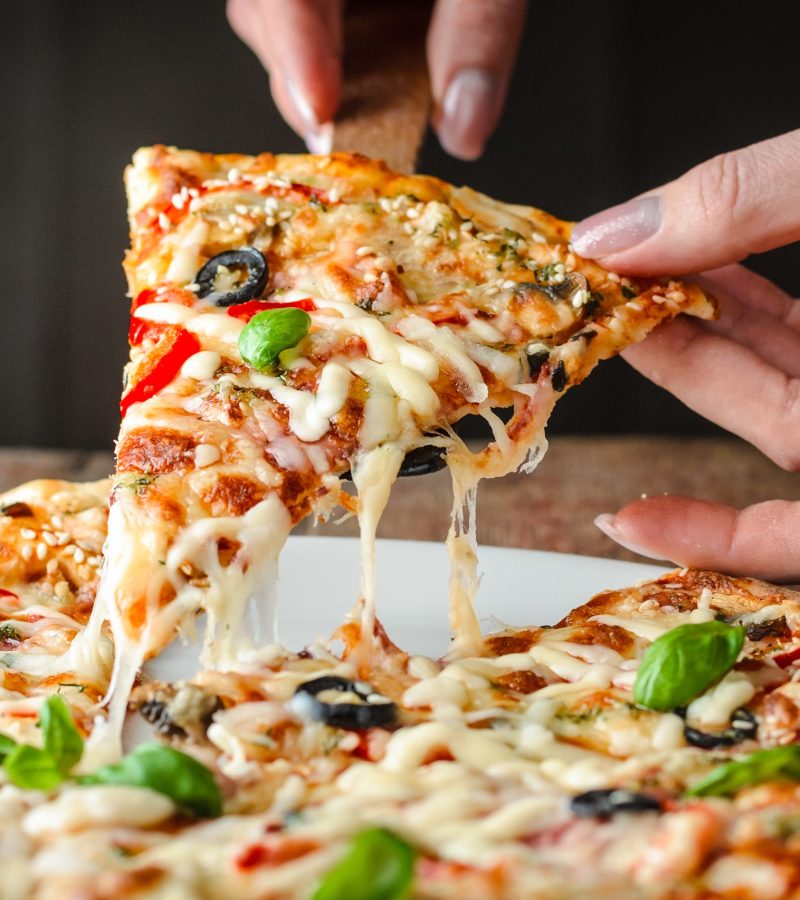 woman's hands takes a piece of pizza with a pulling cheese, close-up